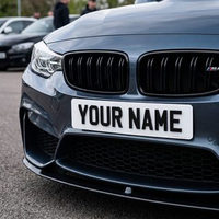 White 4D show plate fitted to the front of a BMW, raised black letters catching the light