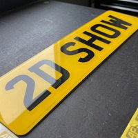 Yellow 2D show plate close up, showing the clean flat printed lettering