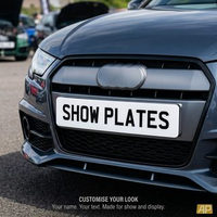 White 2D show plate fitted to the front of an Audi, flat black lettering