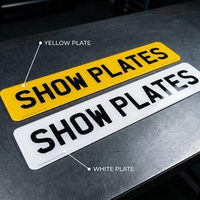 White front and yellow rear 2D show plates side by side, both with flat lettering